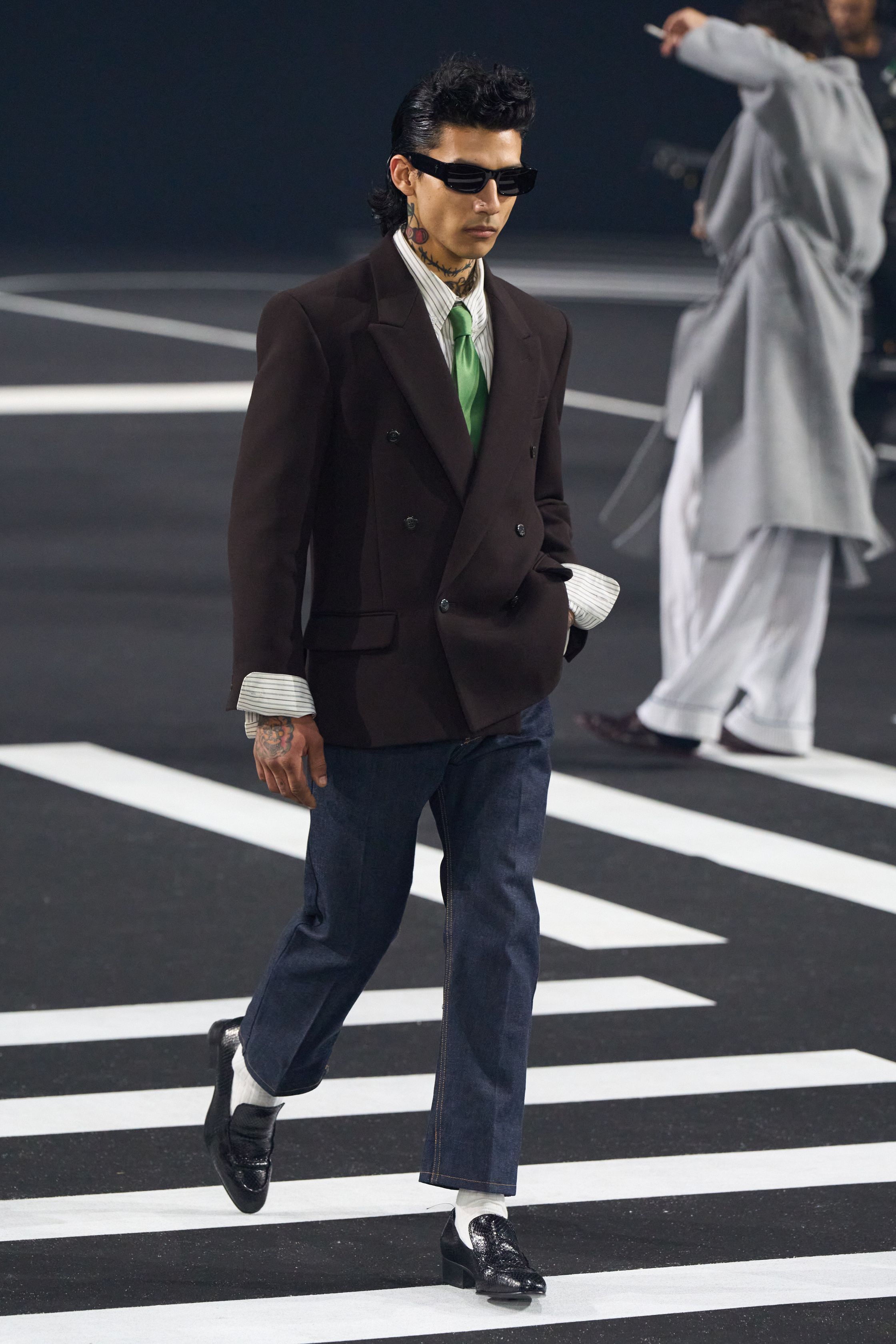 Willy Chavarria 2026秋冬以街头、宗教与拉丁文化为核心，构建出一场强烈的社会现实叙事。宽阔廓形、制服化西装与运动元素并置，模特行走于仿城市街道的场景中，服装成为身份、阶级与尊严的视觉象征。系列情绪直接而有力，将边缘群体的存在感推至聚光灯中心，时装在此成为政治语言-顽石频道趋势研究